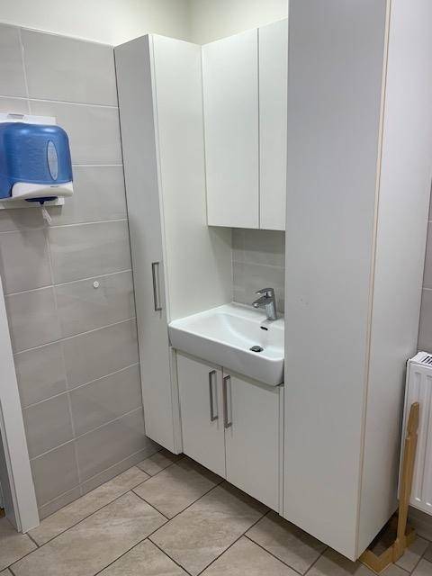 Sauberer Toilettenraum mit Waschbecken, Unterschrank und Wandfliesen in neutralen Farbtönen, gut gepflegt und hell.