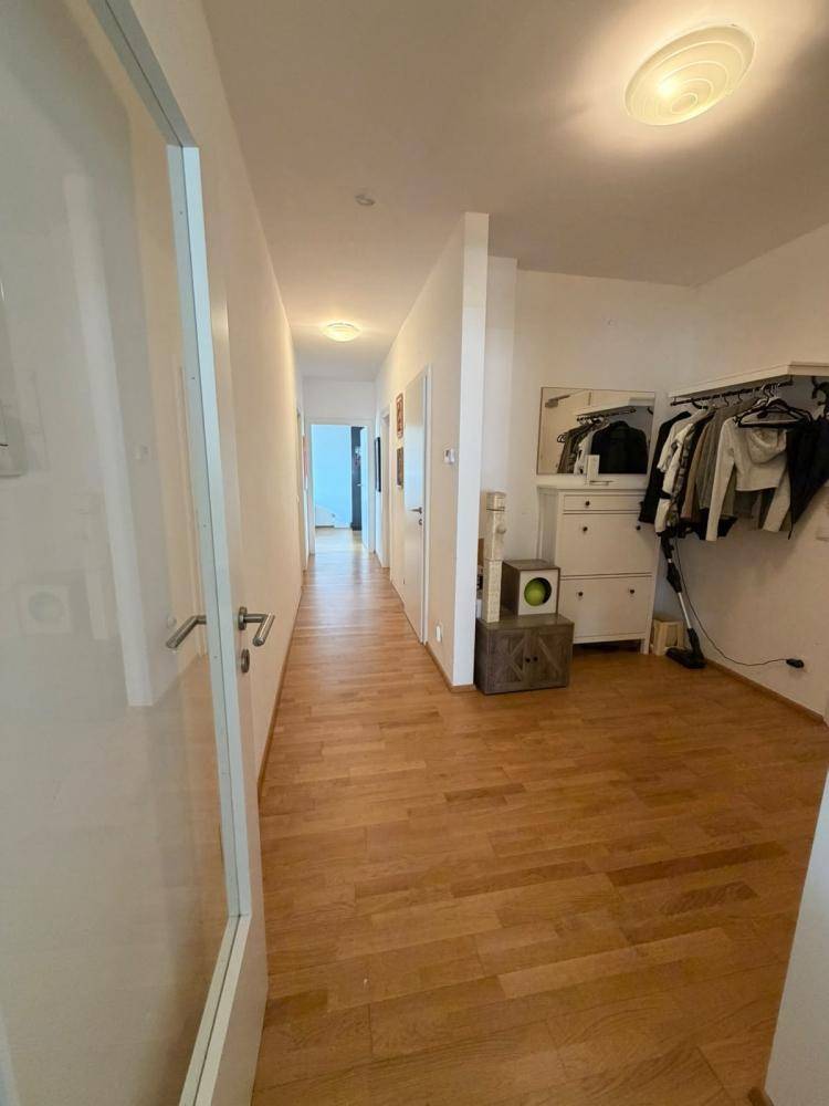 Heller Flur mit Parkettboden und Garderobenbereich, der zu weiteren Räumen führt.
