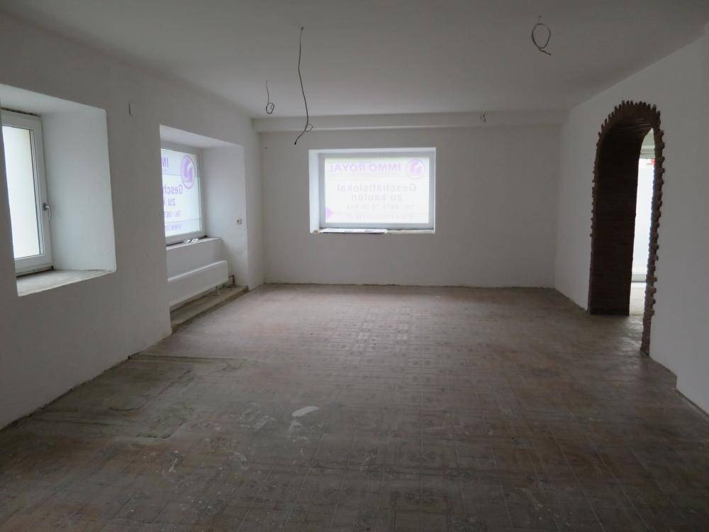 Großer, leerer Raum mit Fliesenboden und zwei Fenstern, bereit für den Ausbau und die Gestaltung.