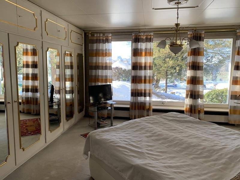 Helles Schlafzimmer mit großen Fenstern, Einbauschränken und Blick nach draußen.