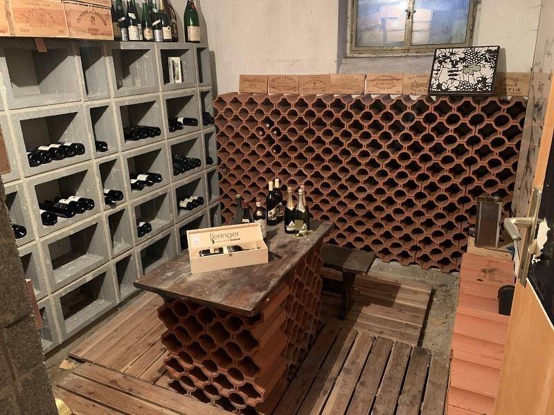 Rustikaler Weinkeller mit zahlreichen Flaschenregalen und Holzboden.