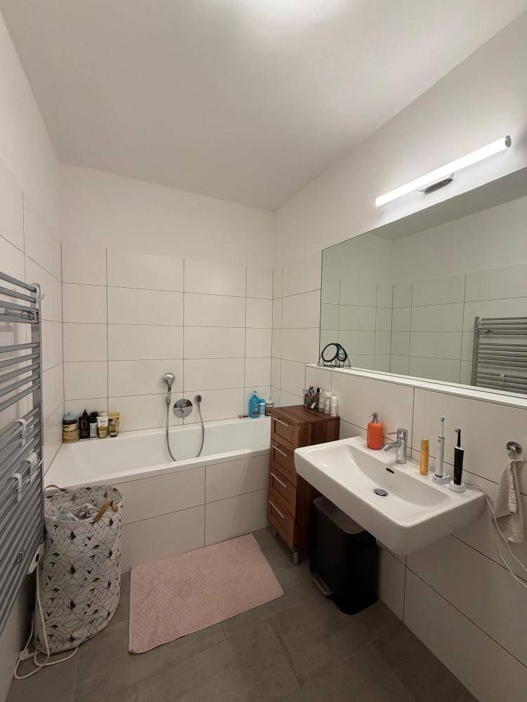 Geräumiges Badezimmer mit Badewanne, modernem Waschbecken und großem Wandspiegel.