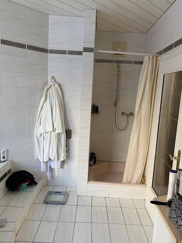 Badezimmer mit Duschbereich, hellen Fliesen und Dachschräge.