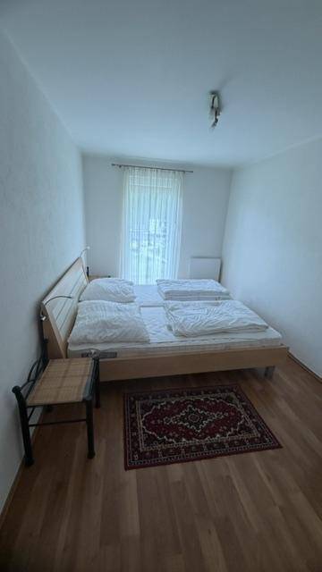 Helles Schlafzimmer mit Doppelbett und warmem Holzfußboden, ideal für erholsame Nächte.