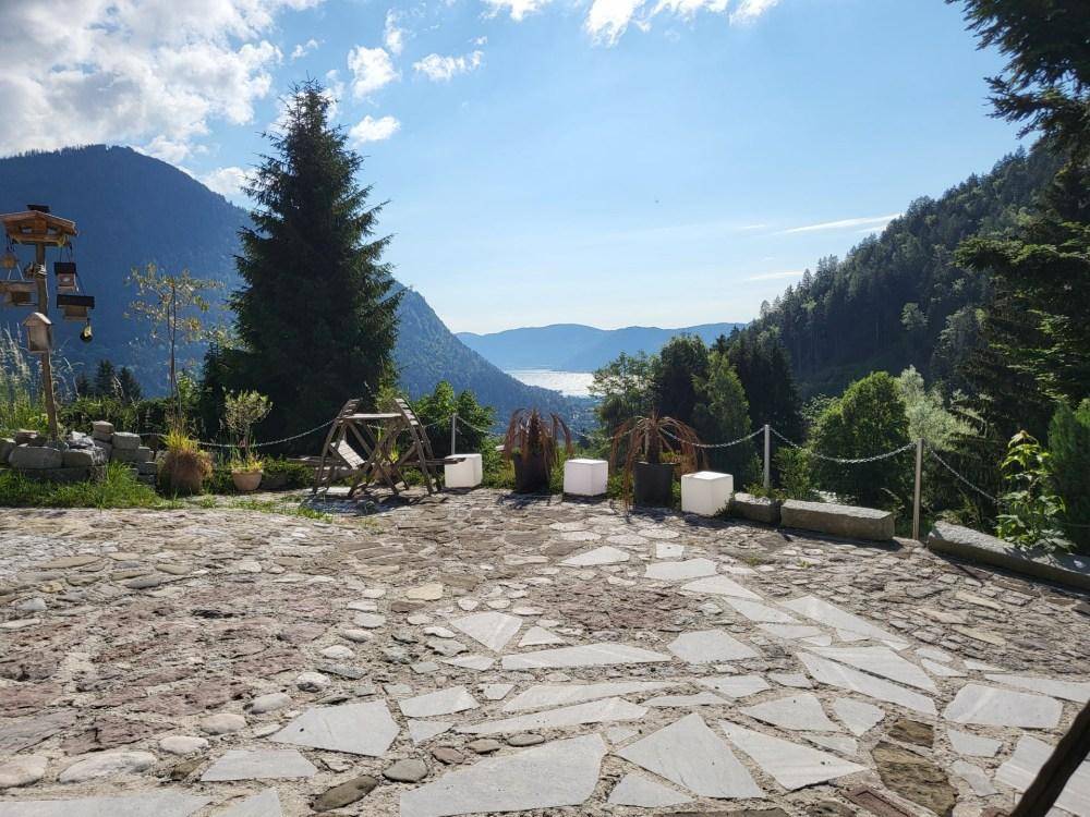 Große gepflasterte Terrasse mit Blick auf einen See und die umliegenden Berge.