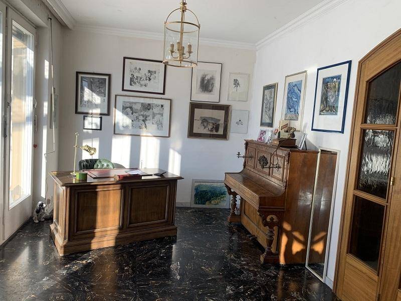 Elegantes Arbeitszimmer mit dunklem Boden, Holzschreibtisch und Klavier.