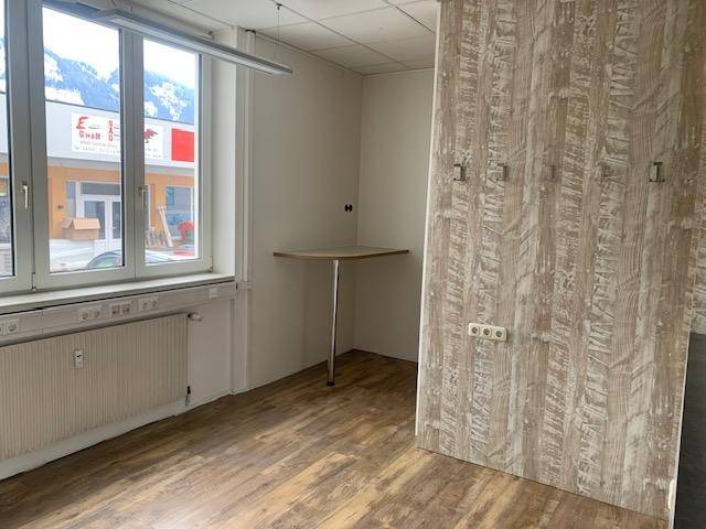 Kleinerer Büroraum mit Fenster, Heizung und einem einfachen Wandtisch, gut beleuchtet und funktional eingerichtet.