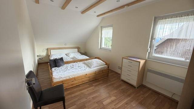 Schlafzimmer mit Holzbalkendecke, Holzboden und schrägen Wänden im Dachgeschoss.