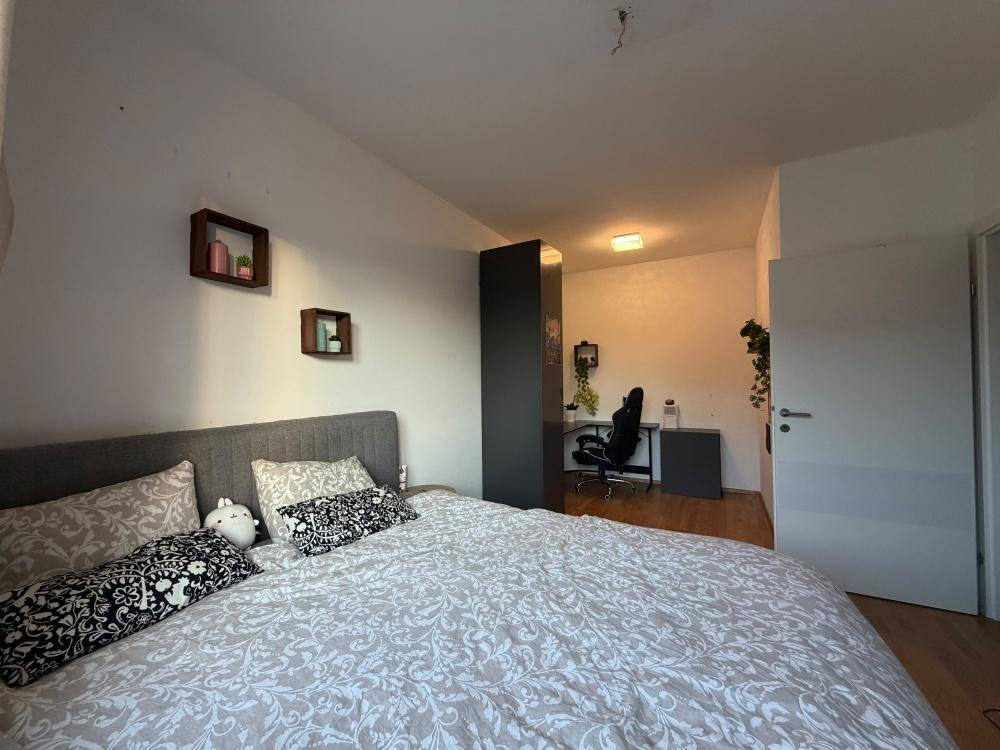 Gemütliches Schlafzimmer mit Doppelbett und separatem Arbeitsbereich im Hintergrund.