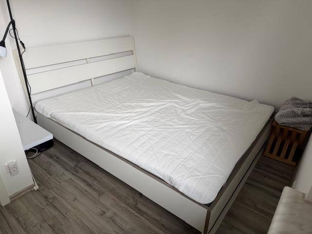Schlafzimmer mit modernem Doppelbett und Laminatboden.