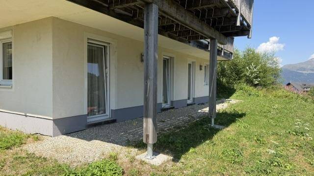 Erdgeschoss des Hauses mit mehreren Zugängen und einer kleinen Kiesfläche, umgeben von Gras.