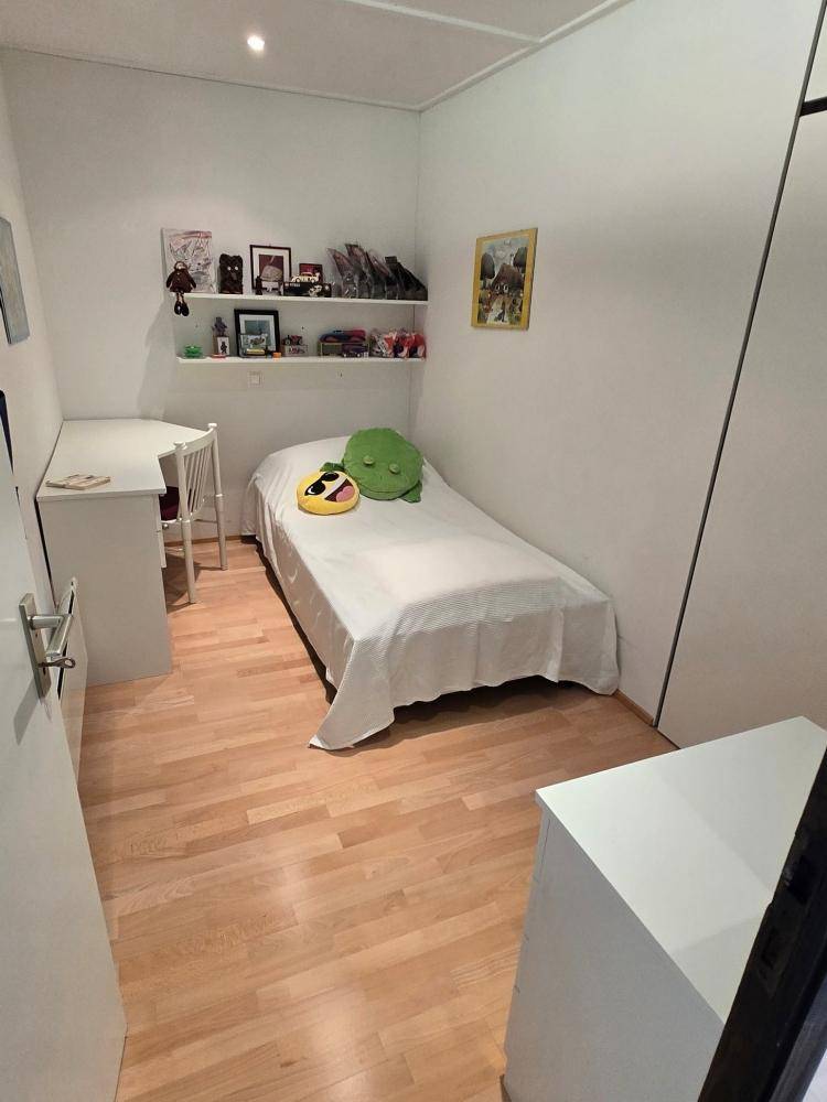 Kleines Schlafzimmer mit Einzelbett, Schreibtisch und Holzboden.