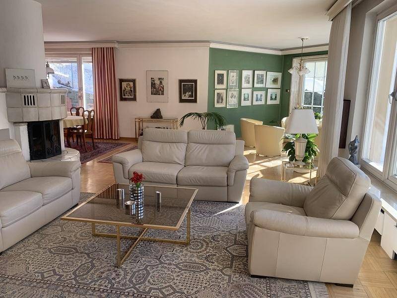 Geräumiger Wohn-Essbereich mit beigen Ledersofas, Kachelofen und Parkettboden.