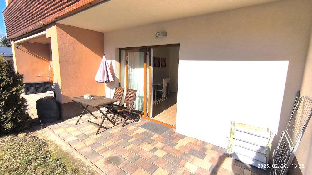 Sonniger Terrassenbereich mit Holztisch und Stühlen, ideal für entspannte Stunden im Freien.