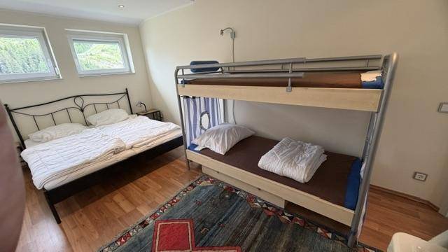 Kinderzimmer mit Doppelbett und Etagenbett, ausgestattet mit Holzboden und Teppich.