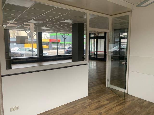 Innenansicht des Geschäftsraums mit Blick auf die großen Schaufenster und die Straße, die eine helle Arbeitsumgebung schafft.