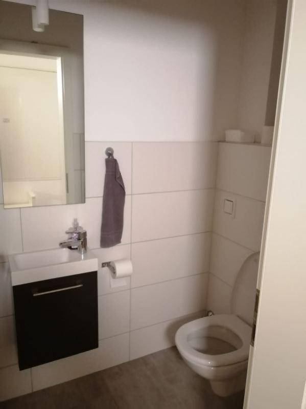 Separates WC mit Waschbecken, Spiegel und Wandfliesen.