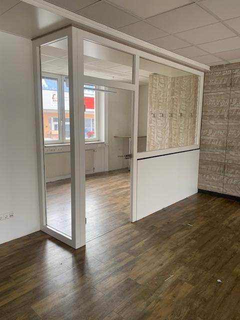 Abgetrennter Bürobereich mit Glaswand und Holzelementen, der Privatsphäre und Licht bietet, ideal für konzentriertes Arbeiten.