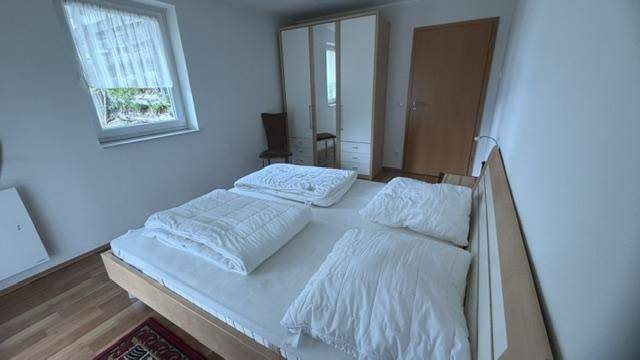 Schlafzimmer mit Doppelbett, großem Kleiderschrank und hellem Holzfußboden.