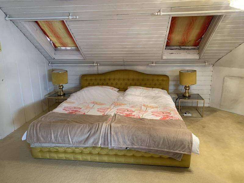 Helles Schlafzimmer im Dachgeschoss mit Dachschrägen und zwei Dachfenstern.
