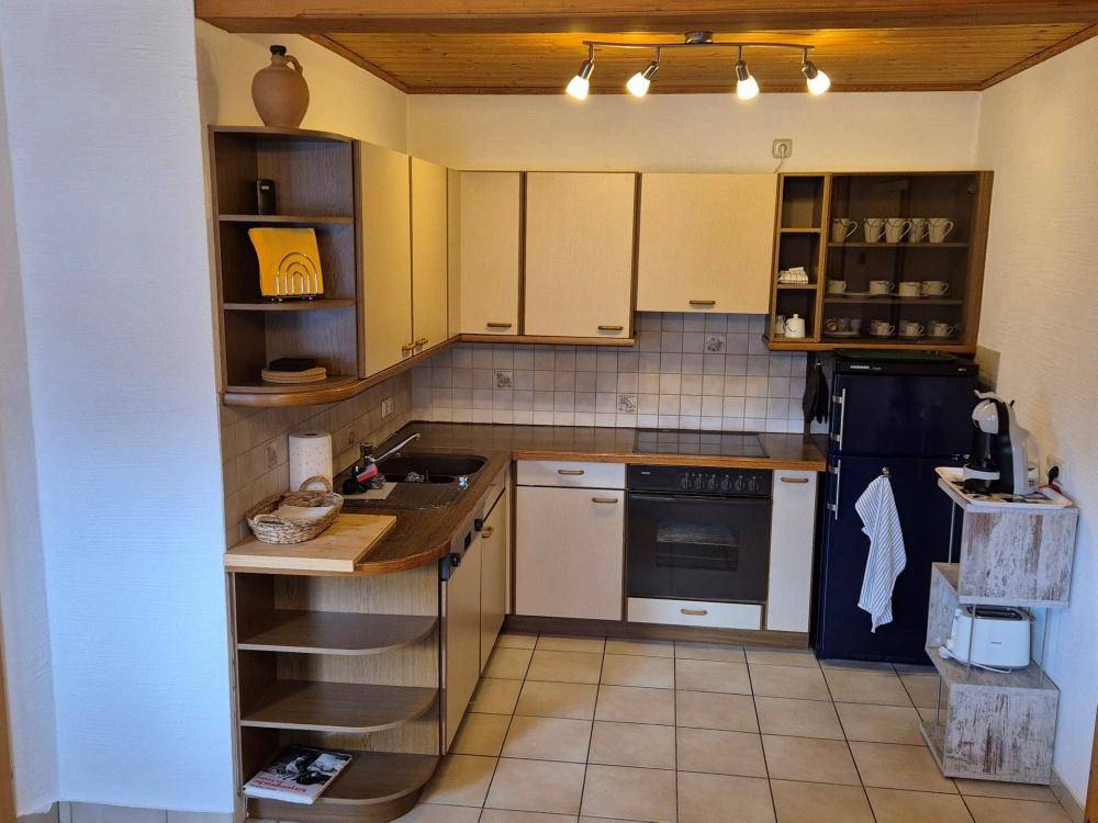 Gemütliche Küche mit Holzdecke, Fliesenboden und integrierten Geräten in traditionellem Stil.