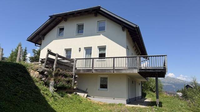 Vorderansicht des Hauses mit Balkonen und weitem Blick auf die umliegende Berglandschaft.
