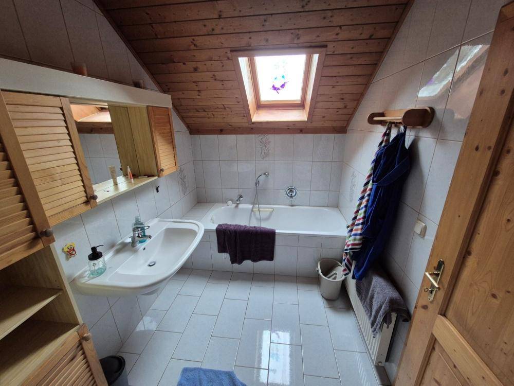 Badezimmer im Dachgeschoss mit Badewanne, Waschbecken und Dachfenster für natürliches Licht.