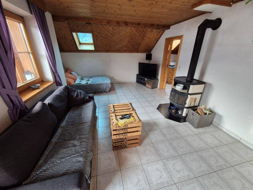 Wohnzimmer im Dachgeschoss mit Kaminofen, Sofa und Dachfenster, gemütlich und hell.