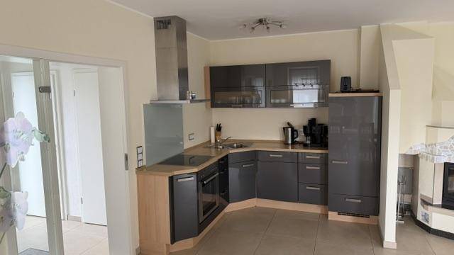 Moderne Einbauküche mit grauen Schränken, Holztheke und Dunstabzugshaube.