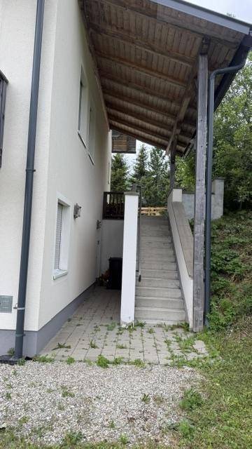 Seitlicher Zugang zum Gebäude mit Außentreppe und gepflastertem Bereich.
