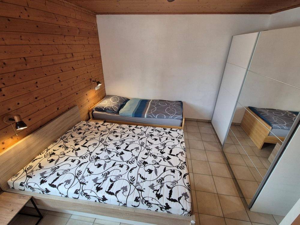 Schlafzimmer mit zwei Betten, Holzvertäfelung und einem großen Spiegelschrank für Stauraum.