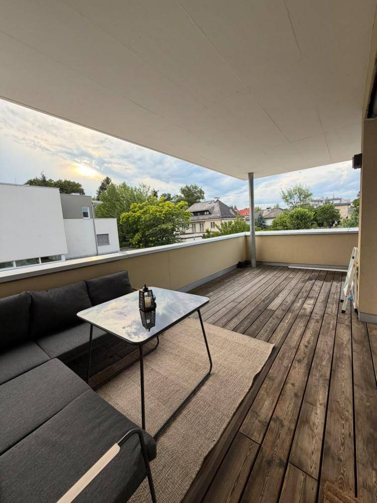 Geräumige Terrasse mit Holzboden, bequemen Loungemöbeln und Blick auf die Umgebung.