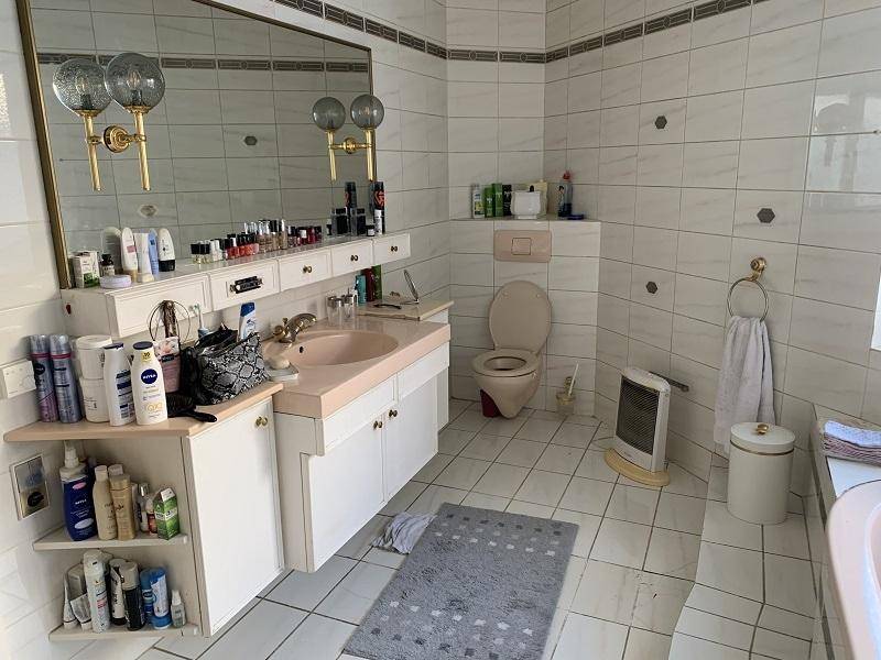 Badezimmer mit Doppelwaschbecken, Toilette und hellen Fliesen.