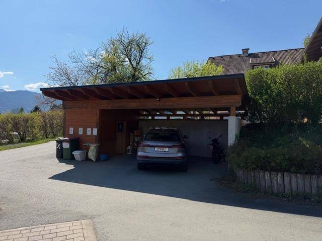 Überdachter Carport mit Parkplatz für ein Auto und Abstellmöglichkeiten.
