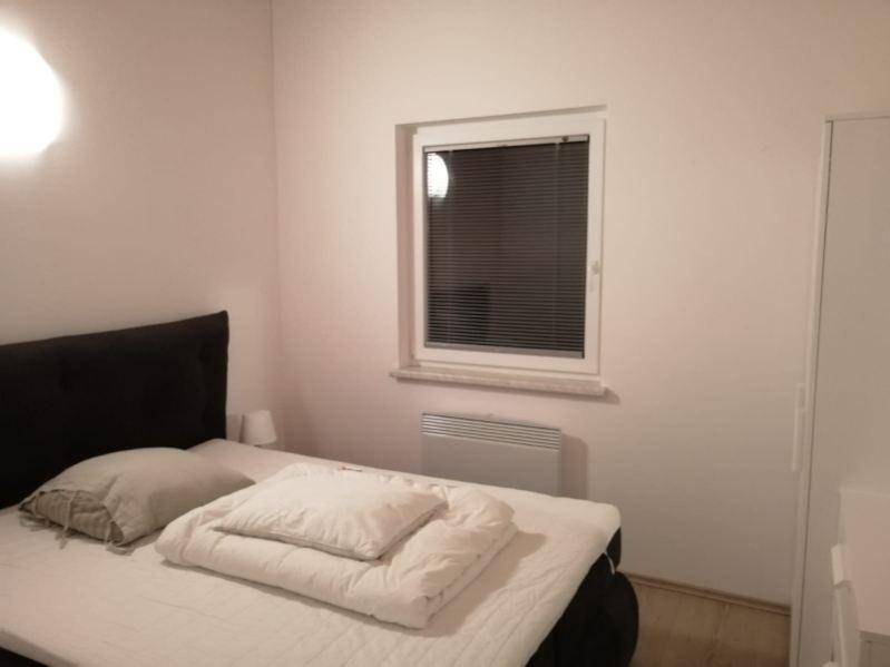 Schlafzimmer mit Doppelbett, Fenster mit Jalousien und Heizkörper.
