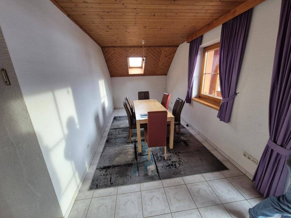 Esszimmer im Dachgeschoss mit Holztisch, Stühlen und Dachfenster, unter der Holzdecke.
