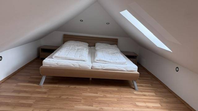 Dachgeschoss-Schlafzimmer mit Doppelbett, Holzboden und Dachfenster für natürliches Licht.