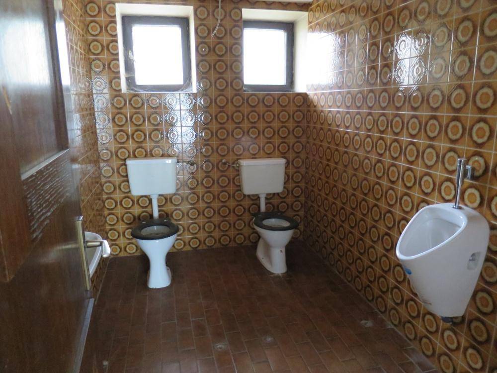 Sanitäre Anlagen mit zwei Toiletten, einem Urinal und gemusterten Fliesen an Wänden und Boden.