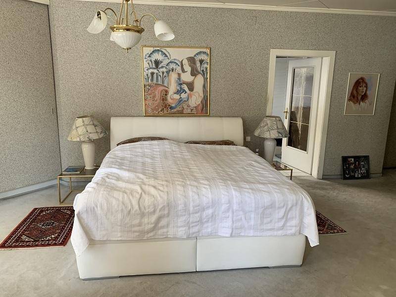 Geräumiges Schlafzimmer mit Doppelbett, gemusterter Tapete und Teppichboden.
