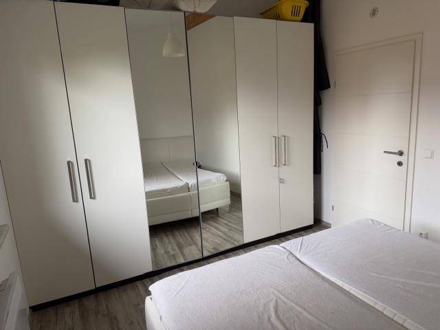 Schlafzimmer mit großem Kleiderschrank mit Spiegeltüren und Doppelbett.