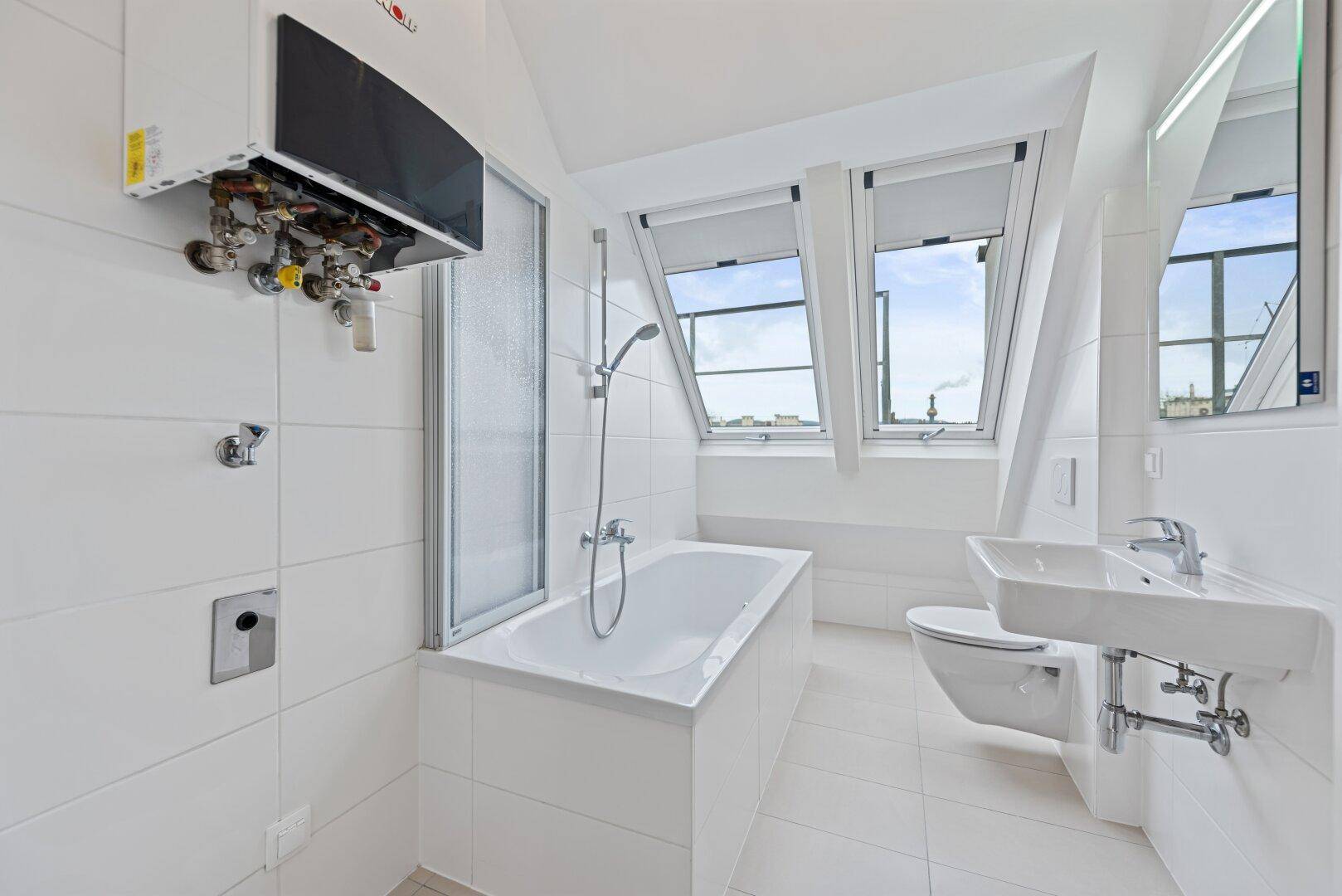 Modernes Badezimmer mit Badewanne, Dusche, WC und Dachfenstern für natürliches Licht.