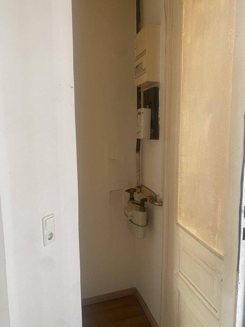 Ein Nischenbereich in einem Flur mit sichtbaren Strom- und Gaszählern sowie Leitungen.