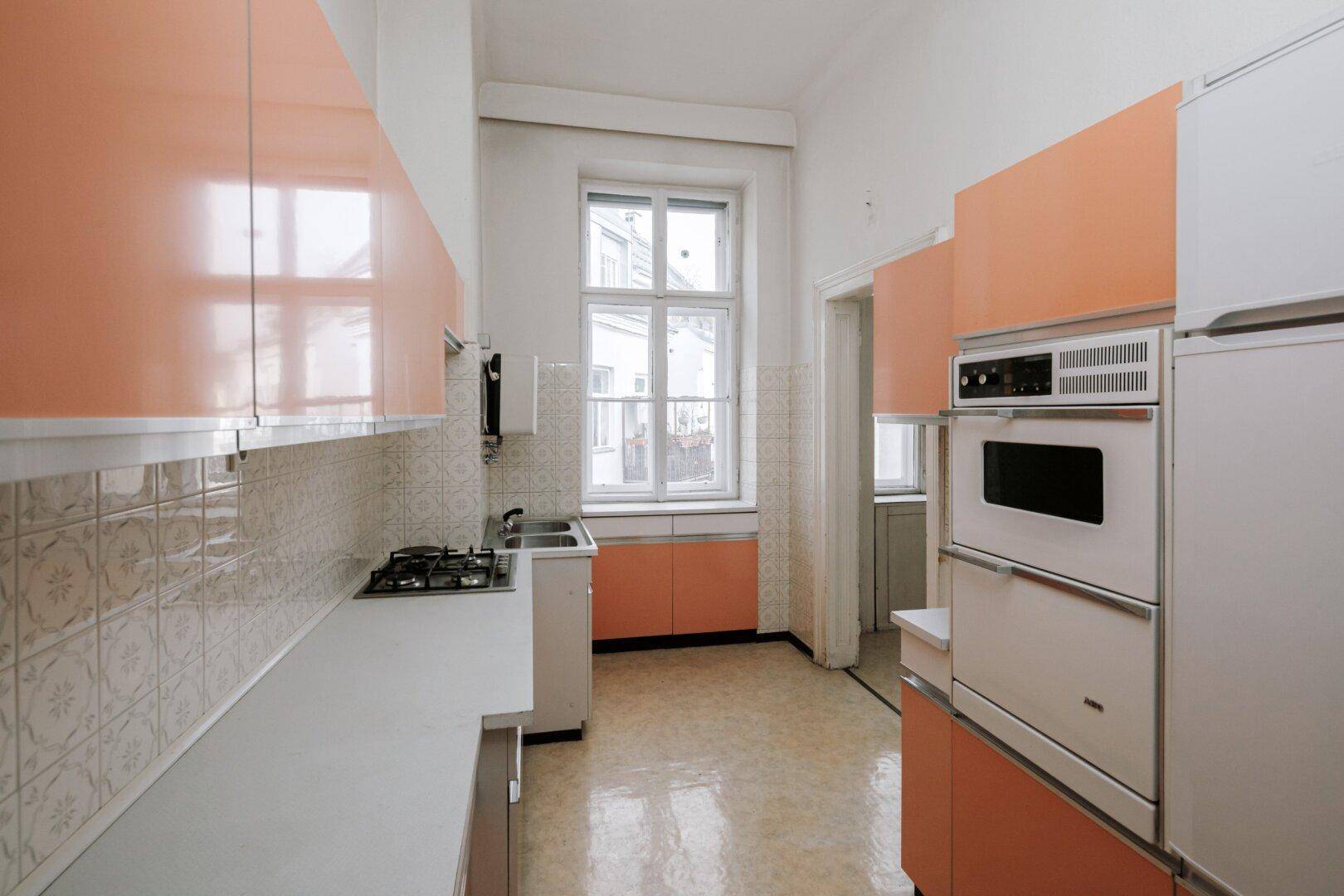Küche im Vintage-Stil mit orangefarbenen Schränken, Gasherd und Einbaugeräten.