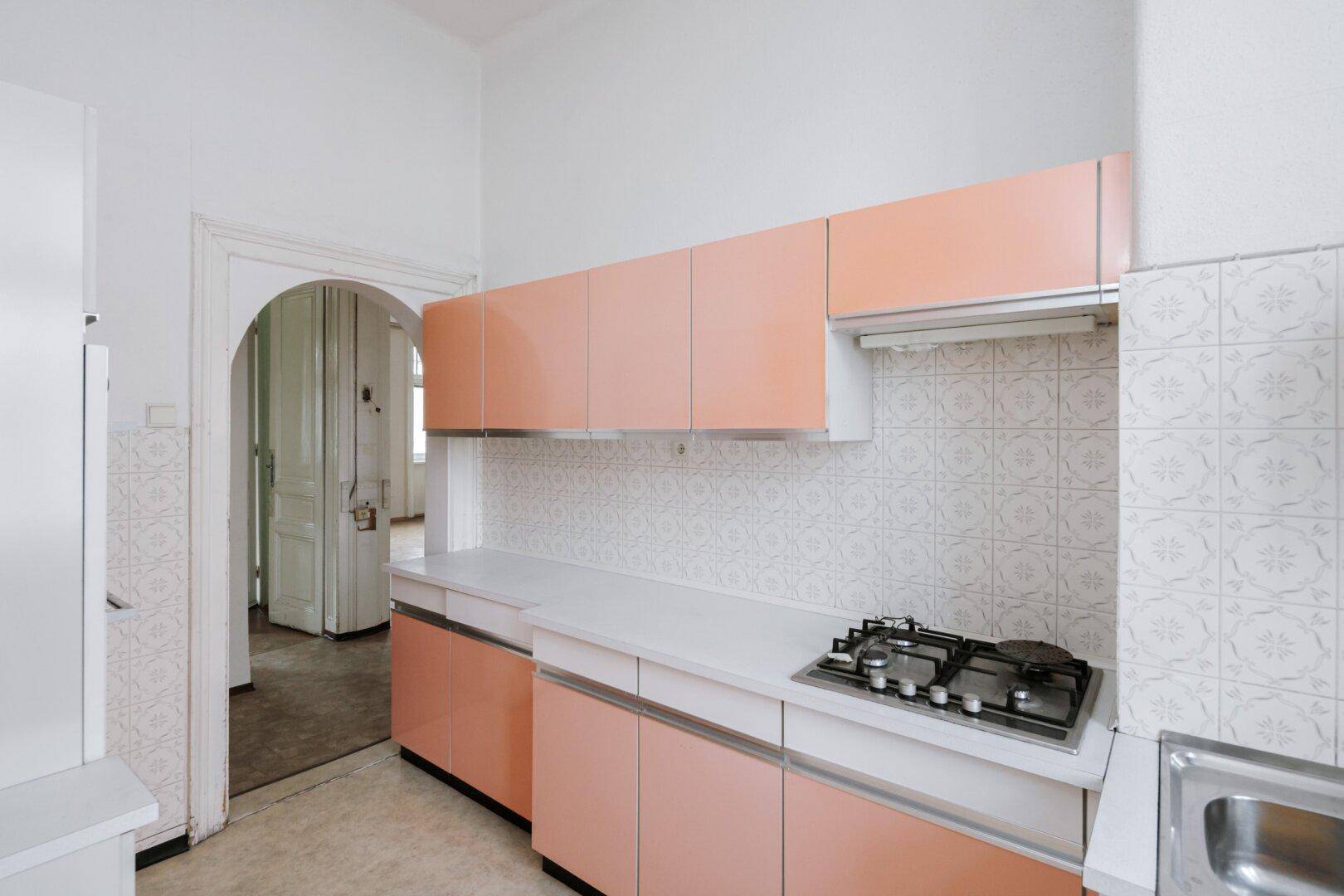 Küche im Vintage-Stil mit orangefarbenen Schränken, Gasherd und gemusterten Fliesen.