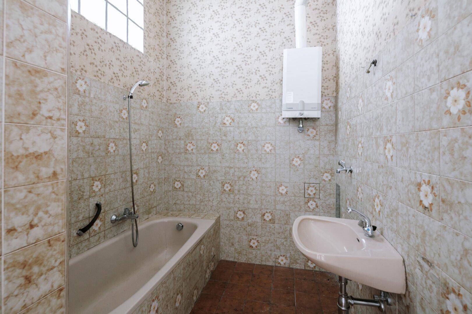 Badezimmer mit Badewanne, Waschbecken und gemusterten Fliesen im Retro-Stil.