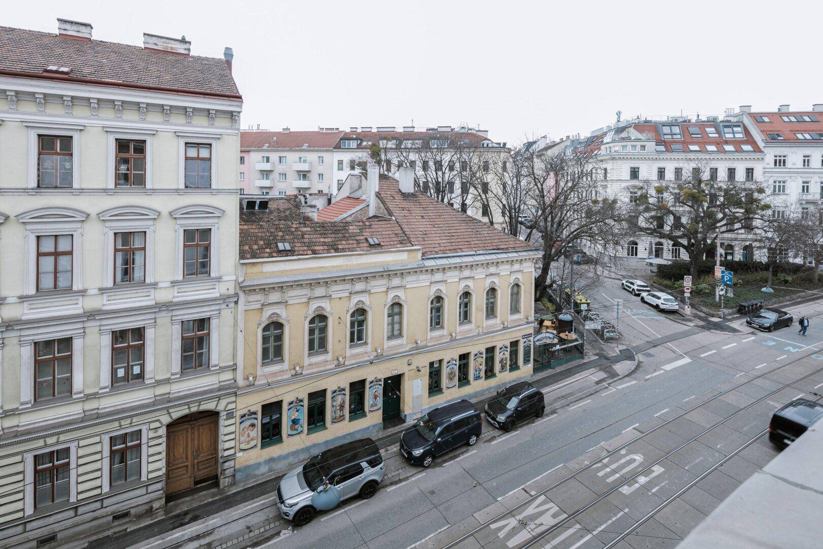 Blick von oben auf eine belebte Stadtstraße mit historischen Gebäuden und Verkehr.
