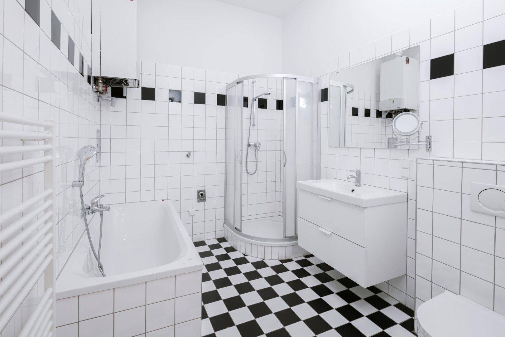 Modernes Badezimmer mit Badewanne, Duschkabine und markantem schwarz-weiß kariertem Fliesenboden.