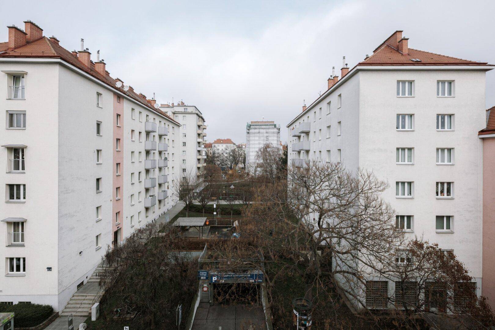Blick auf mehrere Wohngebäude mit Balkonen und einem begrünten Innenhofbereich.