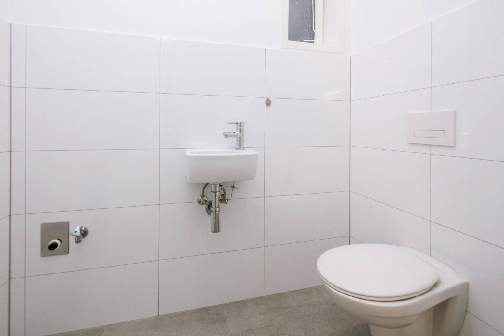 Kleines, modernes Gäste-WC mit wandhängender Toilette und kleinem Waschbecken.