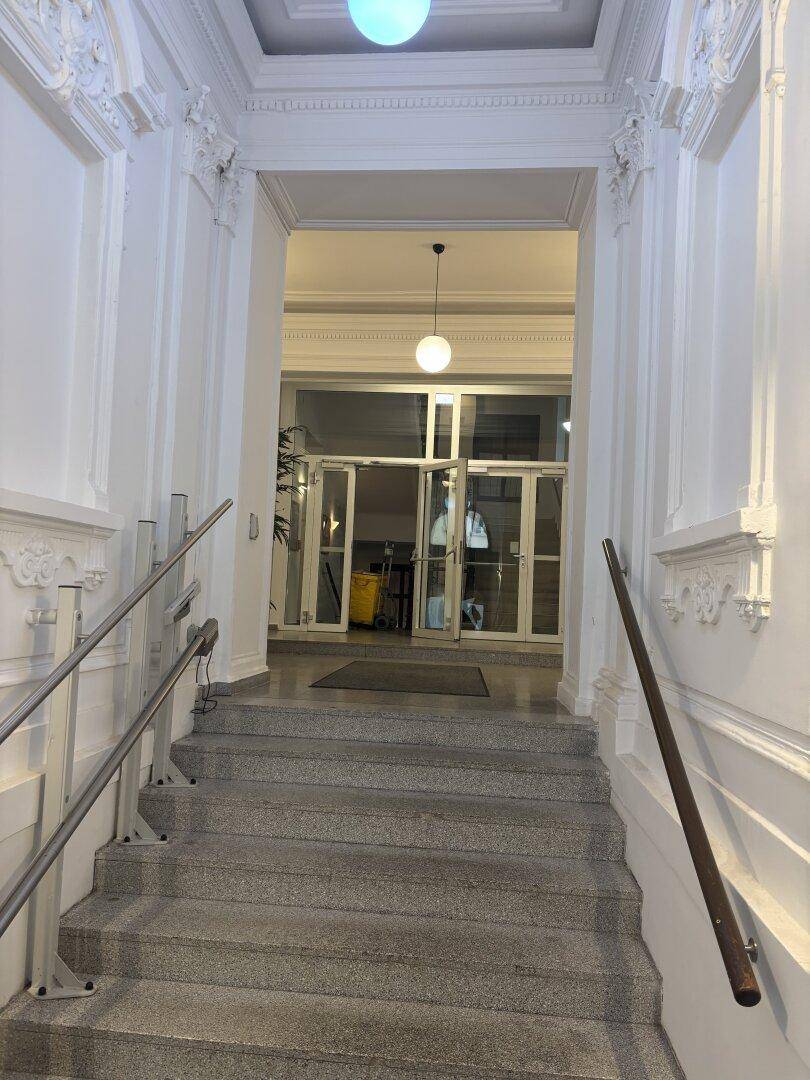 Repräsentativer Eingangsbereich mit Steintreppe, verzierten Decken und modernen Leuchten.